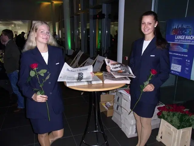 Promoterinnen mit roten Rosen und Zeitungen